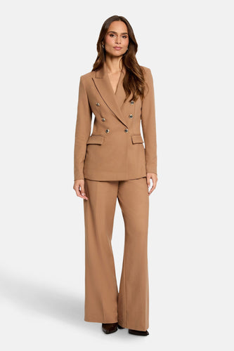 Vrouw in bruin double-breasted pak met wijde pijpen.
