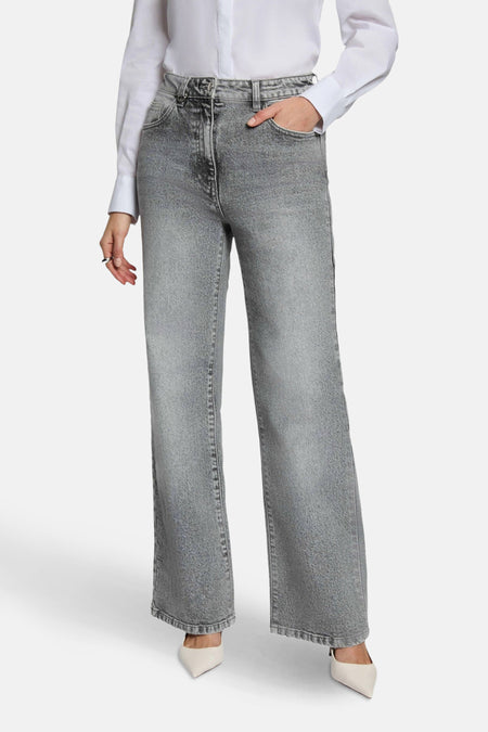 Grijze jeans met wijde pijpen, witte blouse, puntige pumps.