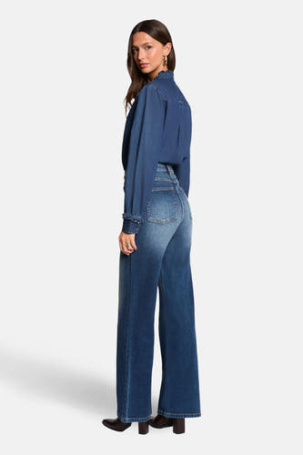 Donkerblauwe wijde jeans van Morgan De Toi, met hoge taille en gedragen met een denim blouse en zwarte hakken.
