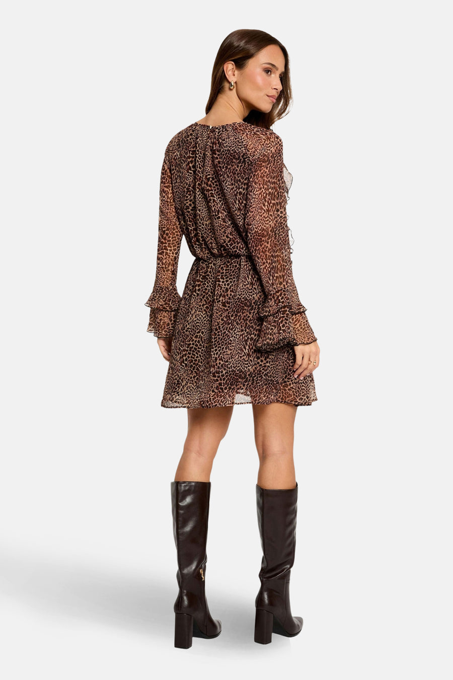 Vrouw draagt bruine luipaardprint jurk met bruine laarzen.