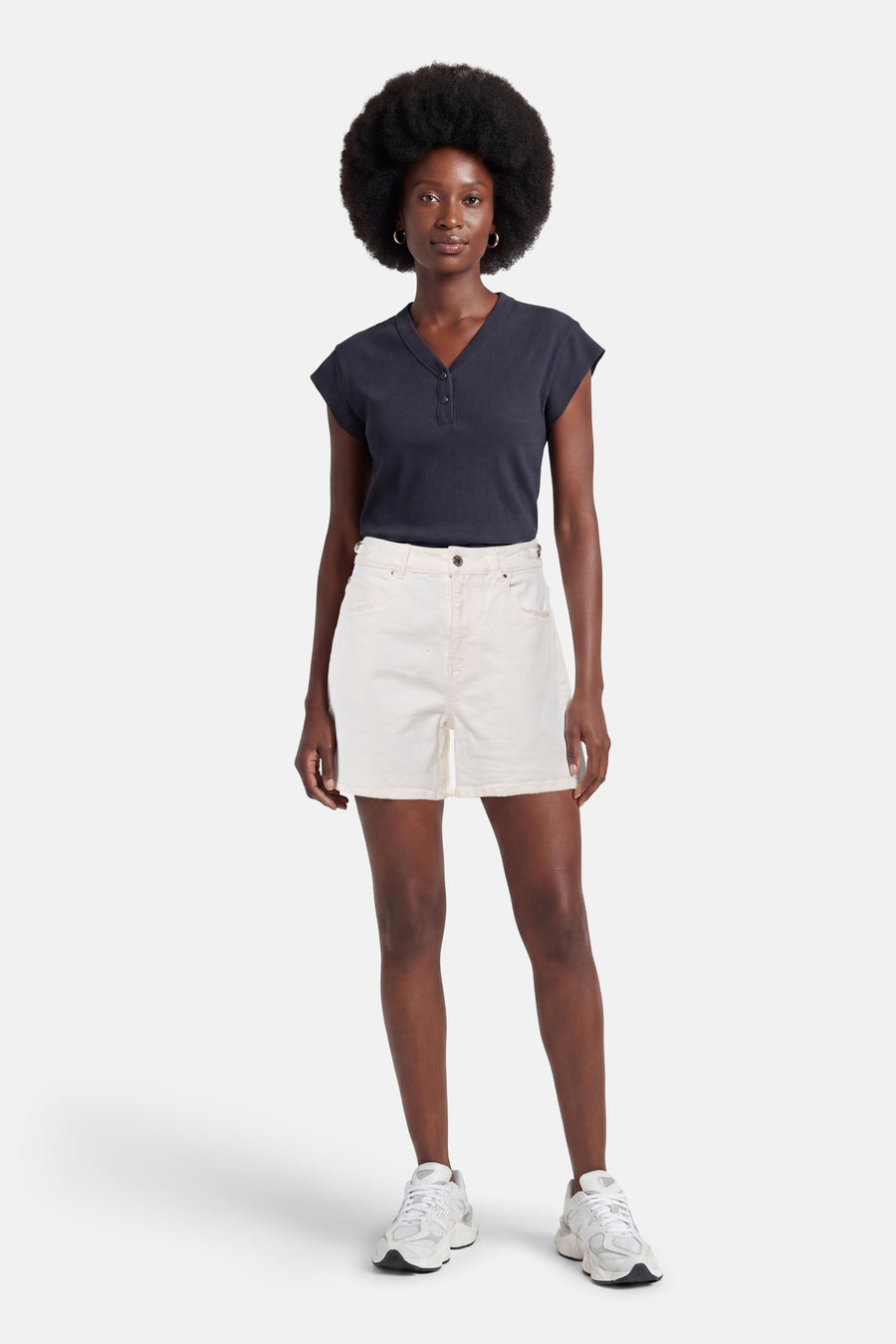 Short en jean blanc de Morgan De Toi, porté par une femme avec un haut bleu marine et des baskets blanches.