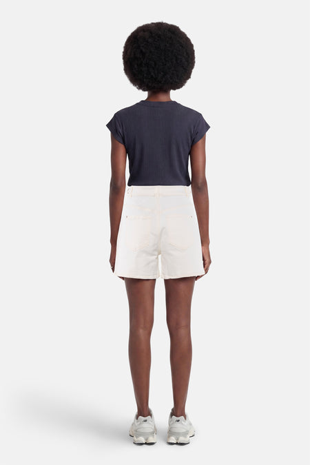 Witte denim short van Morgan De Toi, van achteren gezien op een model met donker geribd T-shirt en lichte sneakers.