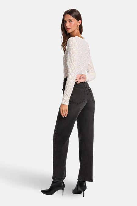 Vrouw in kanten top, zwarte jeans en laarsjes met hak.