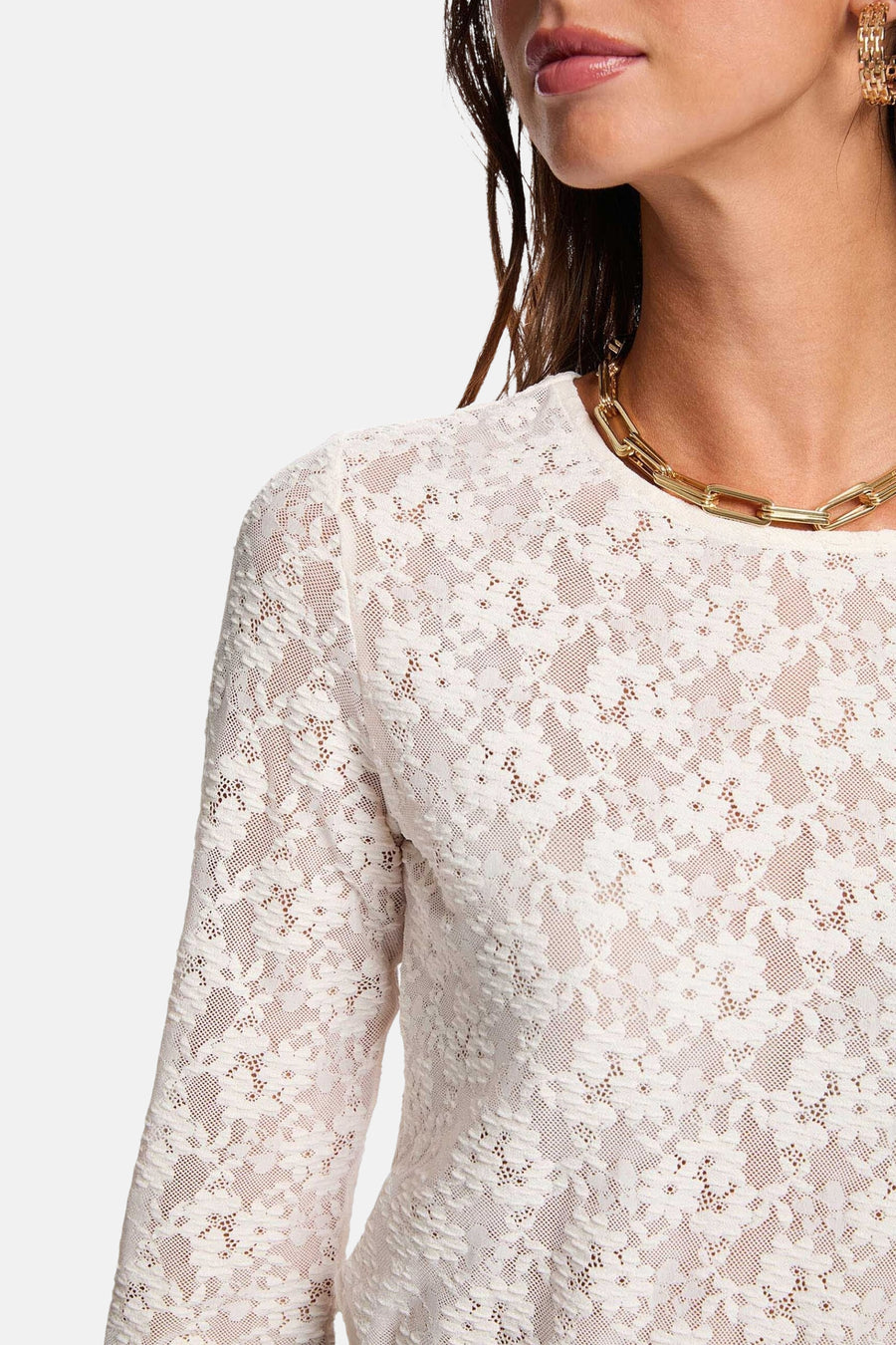 T-shirt écru à manches longues de Morgan De Toi, avec un motif floral sur les bords, associé à une chaîne d'or et des boucles d'oreilles.