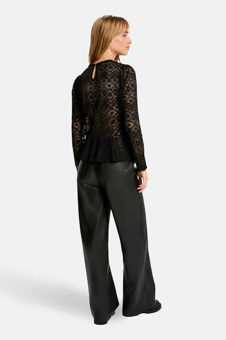 Vrouw, zwart kanten blouse, zwarte leren broek.