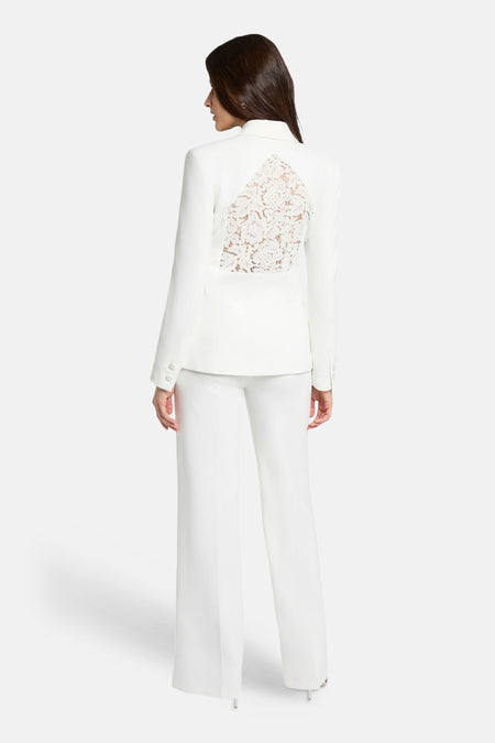 Blazer blanche Morgan De Toi avec empiècement en dentelle au dos, portée avec un pantalon blanc.