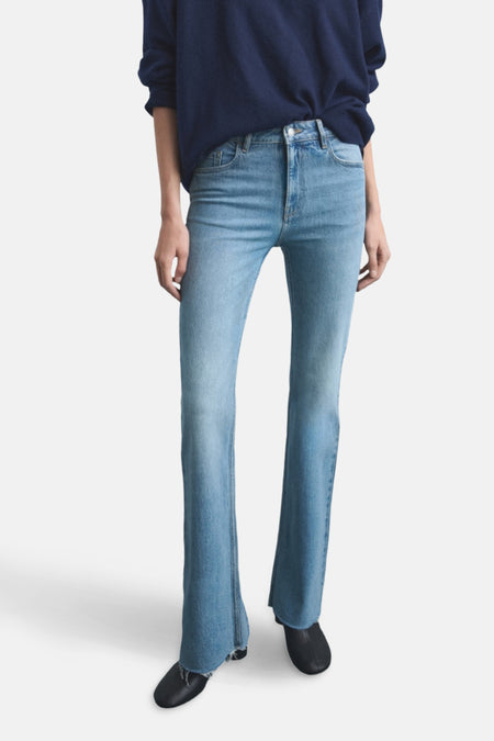 Lichtblauwe flare jeans met donkerblauwe trui en zwarte schoenen.