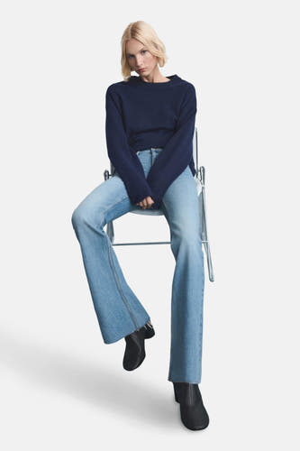 Jean flare bleu clair de MANGO porté avec une chemise bleue foncée et des bottines noires dans un studio.