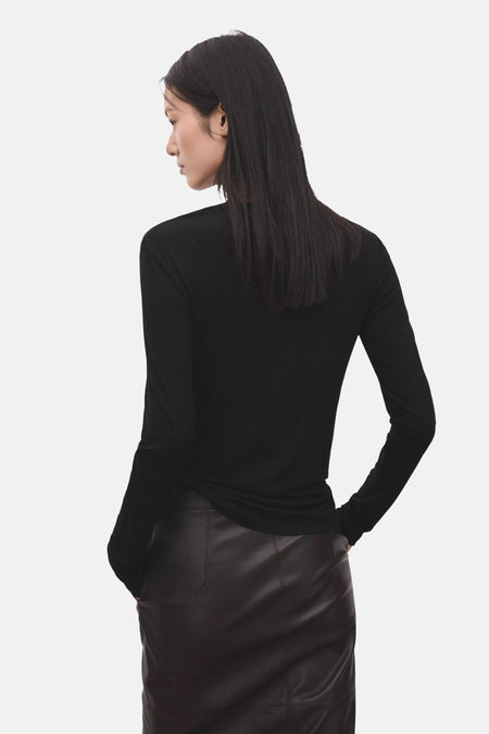 Zwart T-shirt met lange mouwen van MANGO, gedragen door een model in een donkerbruine leren rok, rugzicht.