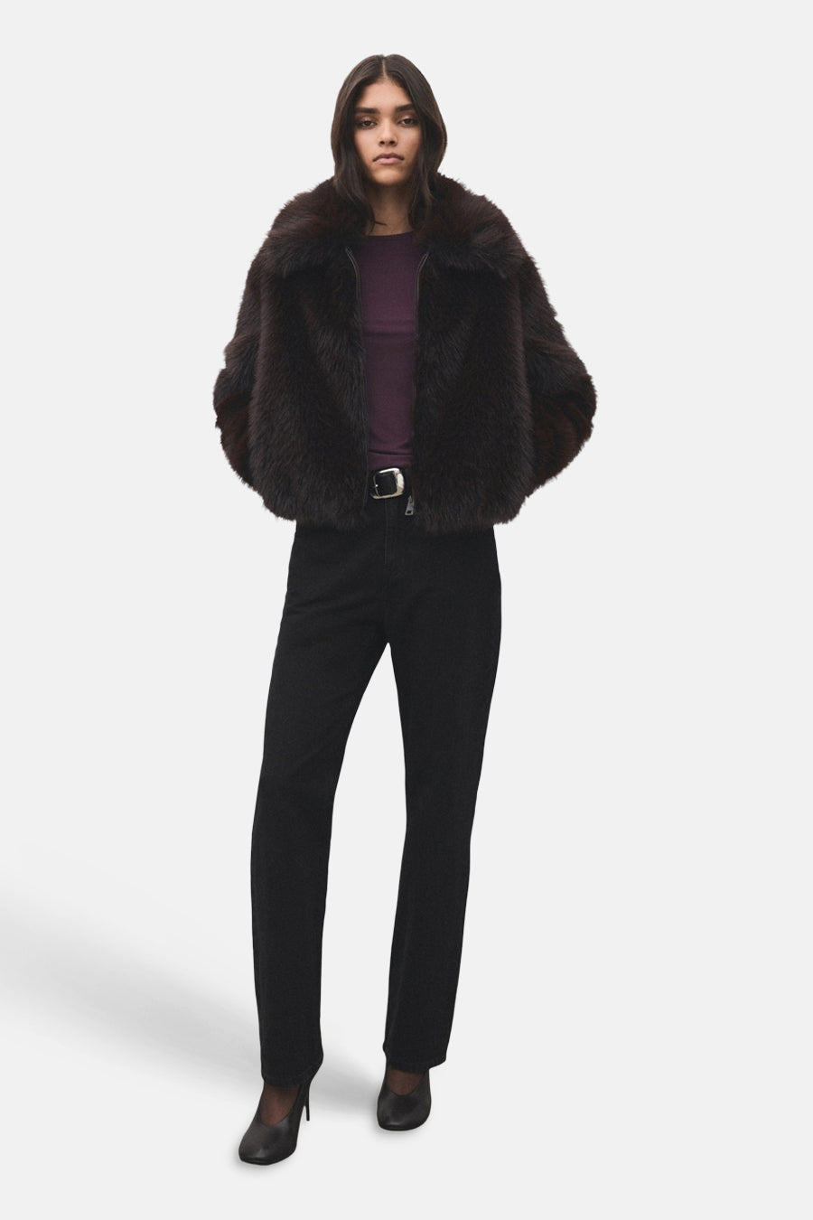 T-shirt à manches longues Bordeaux de MANGO, porté sous une veste en fausse fourrure marron foncé avec un jean noir et des talons.