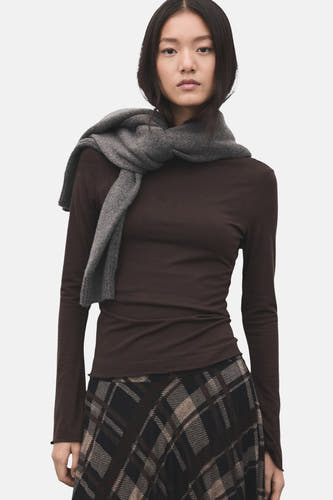 T-shirt marron à manches longues de MANGO, vu par derrière, associé à une jupe longue et des talons noirs.