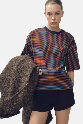 T-shirt multicolore à manches courtes de MANGO, avec des rayures horizontales et porté avec des short noirs.