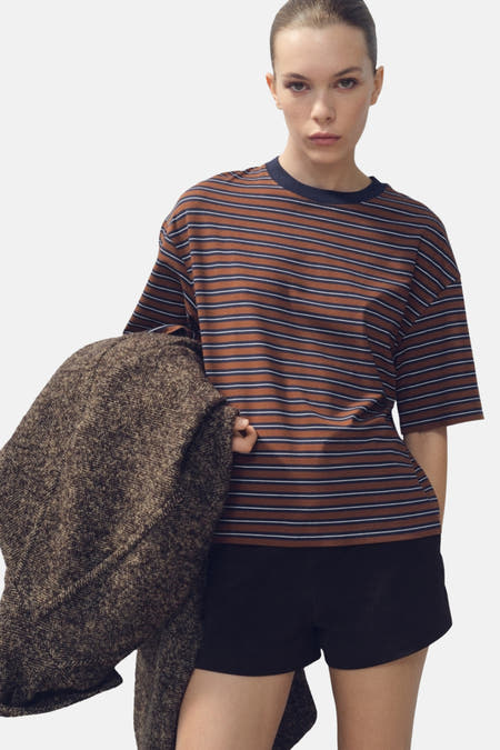 T-shirt multicolore à manches courtes de MANGO, avec des rayures horizontales et porté avec des short noirs.