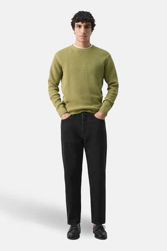 Pull vert à col rond de MANGO, porté avec un jean foncé et des chaussures.