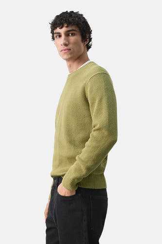 Pull vert à col rond de MANGO, en maille fine et porté avec un jean noir.