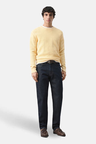 Pull jaune à col rond de MANGO, porté avec un jean foncé et des chaussures marron.