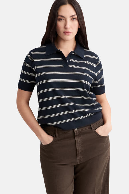 Blauwe polo met korte mouwen van MANGO, met witte horizontale strepen en bruine broek.