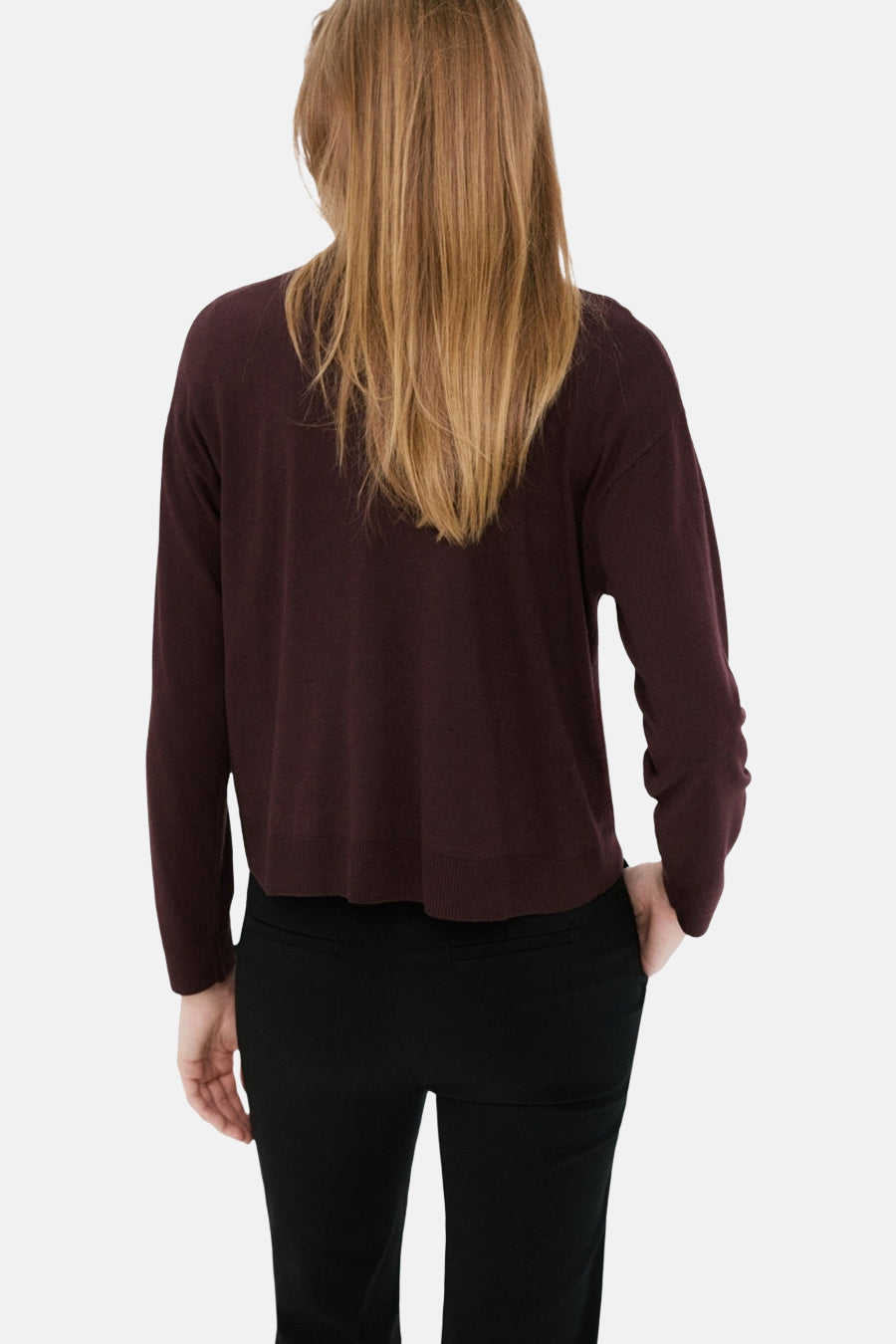 Bordeaux trui met ronde hals van MANGO, gezien van achteren, gecombineerd met een zwarte broek.
