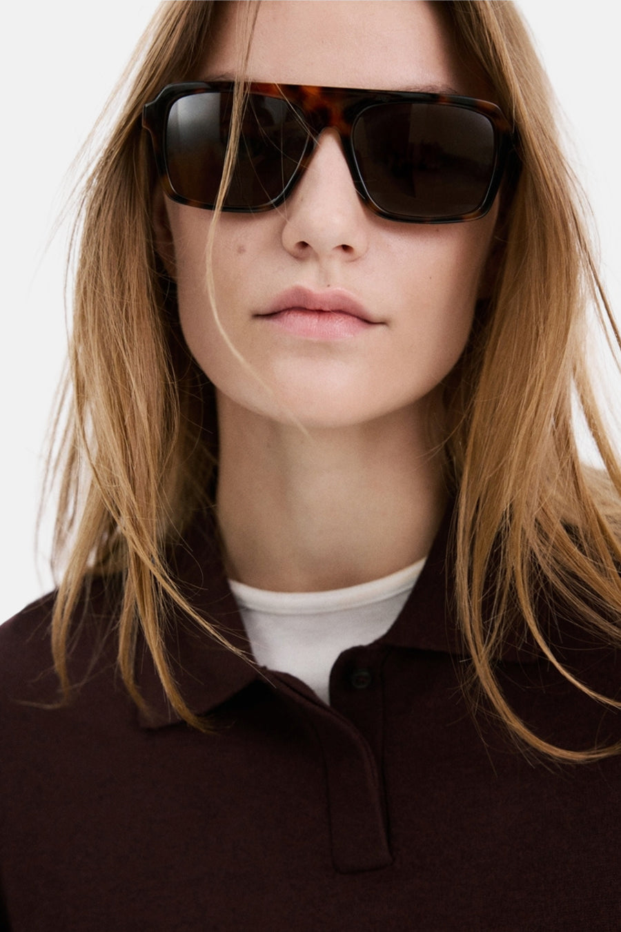 Pull bordeaux à col rond de MANGO, porté sous un polo marron foncé avec un haut blanc en dessous.