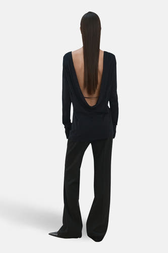Pull noir à col rond de MANGO, avec un décolleté plongeant dans le dos et des manches longues, combiné avec un pantalon noir.