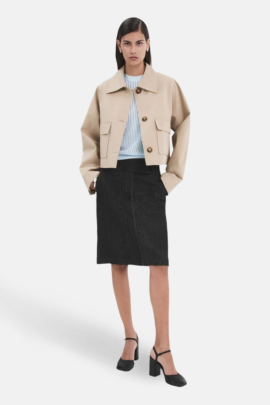 Pull bleu à col rond de MANGO, porté avec une veste courte et une jupe foncée.