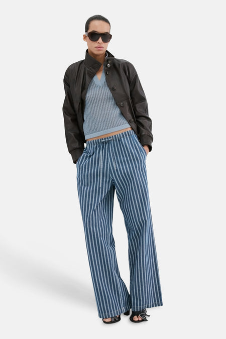 Polo bleu à manches courtes de MANGO, texturée et associée à une veste en cuir et un pantalon rayé.