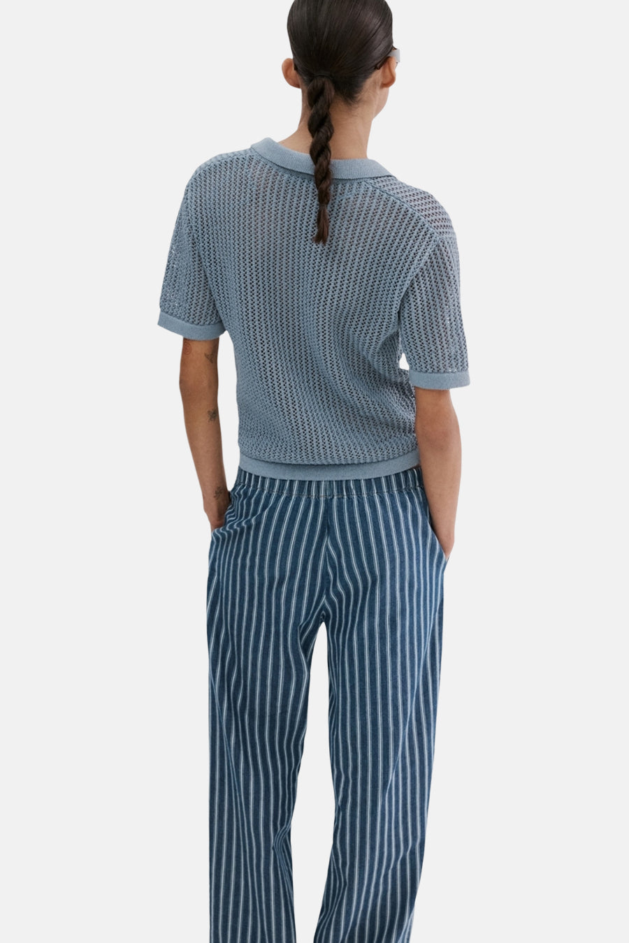 Blauw poloshirt met korte mouwen van MANGO, met een opengebreide textuur en gedragen met gestreepte broek.