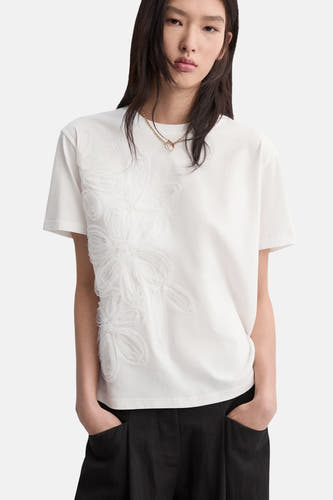 T-shirt blanc de MANGO, vu de dos, combiné avec un pantalon noir évasé.