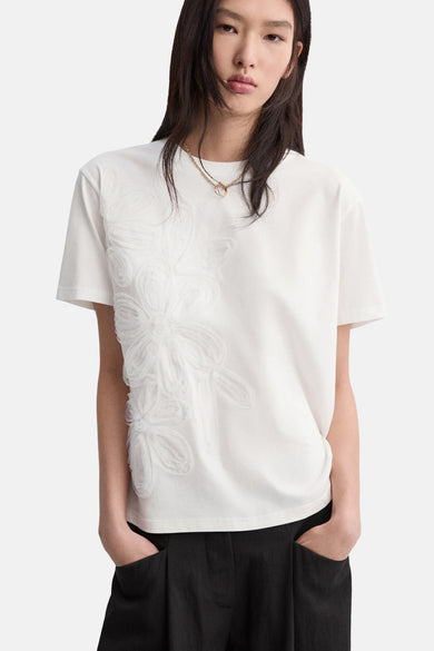 T-shirt blanc de MANGO, vu de dos, combiné avec un pantalon noir évasé.