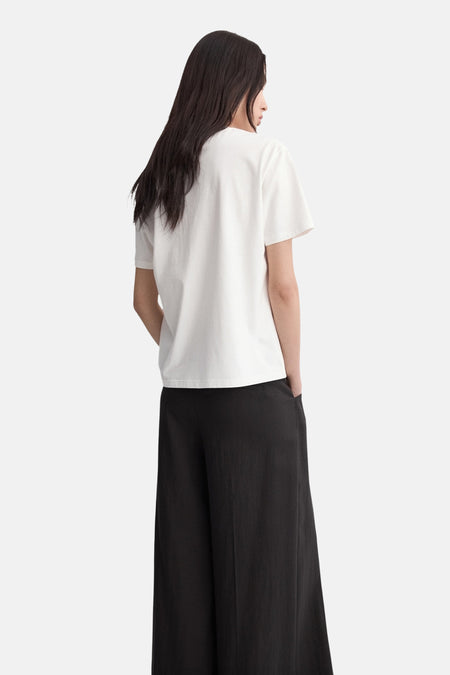 Wit T-shirt van MANGO, gezien van achteren, gecombineerd met zwarte, wijd uitlopende broek.

