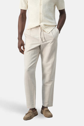 Pantalon écru de MANGO, avec cordon de serrage et poches latérales, combiné avec des mocassins en daim et une chemise en maille.