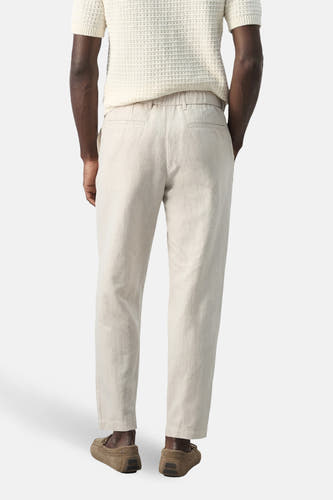 Pantalon écru de MANGO, vu de dos, avec une taille élastique et des mocassins marron.
