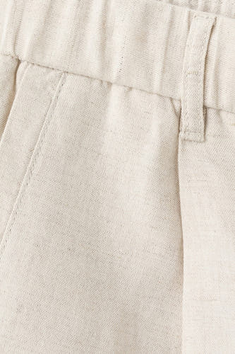Pantalon écru de MANGO, avec taille élastique et passant de ceinture.