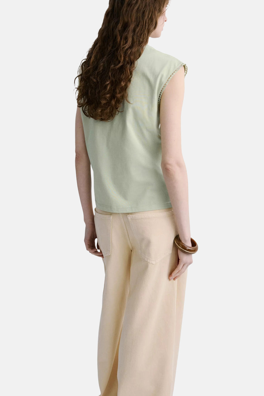 Groene mouwloze top van MANGO, achterzijde, met kant details aan de schouders, gedragen met crèmekleurige broek en houten armband