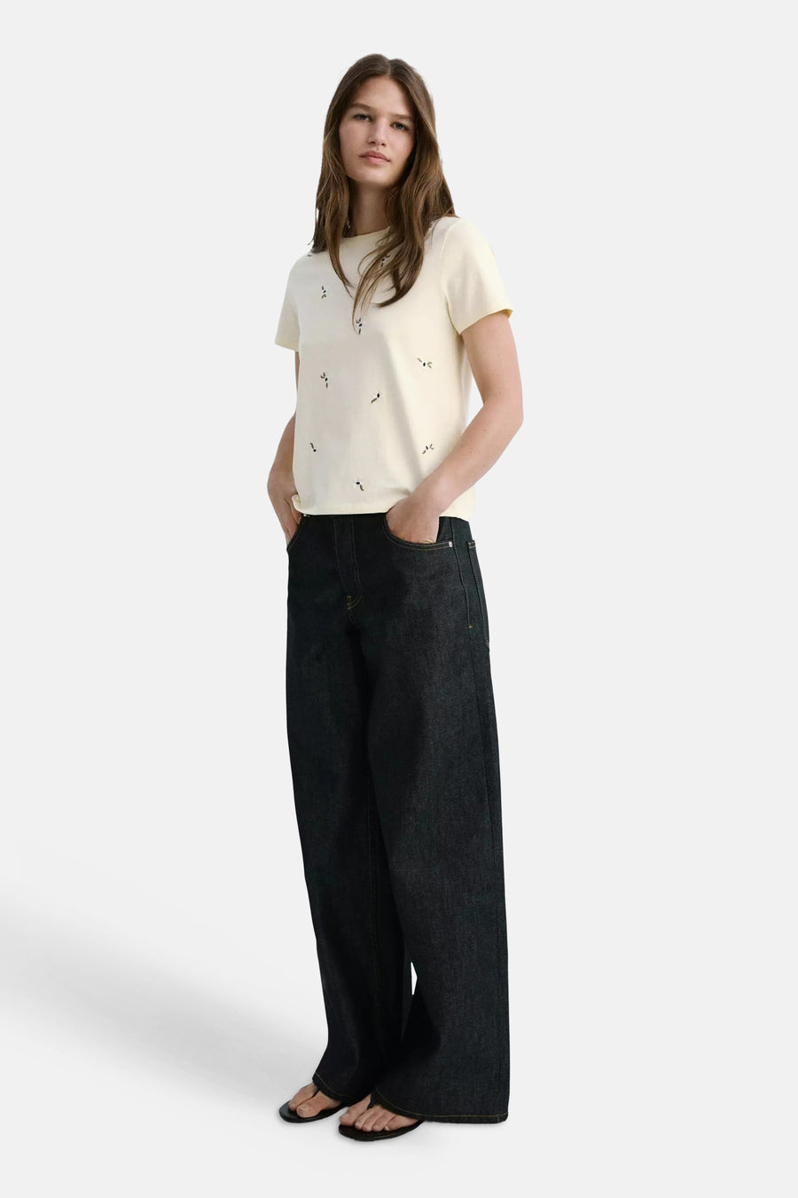 Gele korte mouwen t-shirt van MANGO met kleine bloemmotieven, gedragen met donkere wijde jeans en sandalen, front view