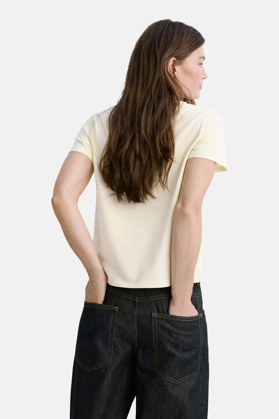 Gele korte mouwen t-shirt van MANGO, achterzijde, gladde stof, model met donkere jeans, handen in zakken