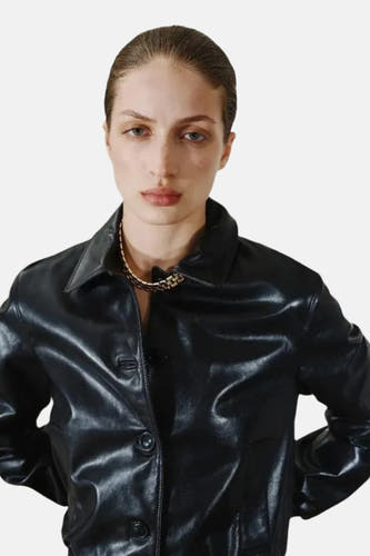 Collier court en or de MANGO, visible porté avec une veste en cuir noire à col et boutons.