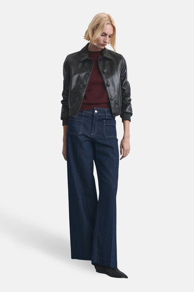 Jean large de denim bleu marine de MANGO, associé à une veste en cuir sombre et à un haut bordeaux.