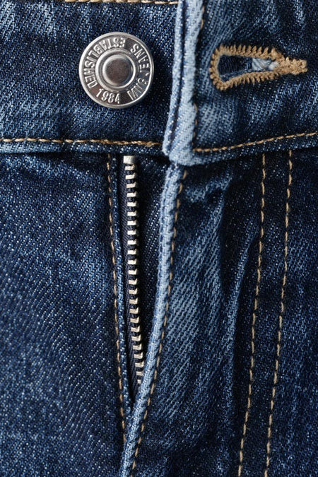 Jean mom bleu marine foncé de MANGO, avec fermeture éclair et détail de bouton, gros plan.