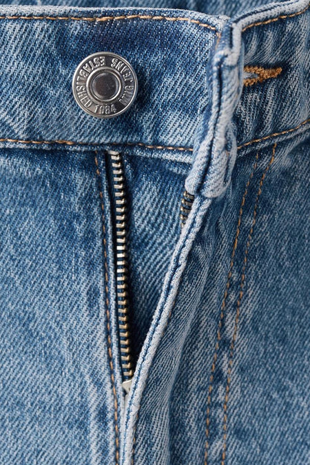 Jean mom en denim bleu moyen de MANGO, avec une fermeture éclair et un détail couleur argent.