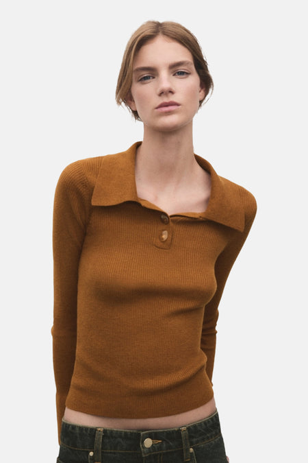 Vrouw draagt bruine ribgebreide trui met kraag.