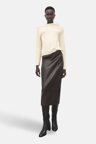 Veste écru avec col rond de MANGO, à motif côtelé et portée avec une jupe en cuir marron et des bottes noires.