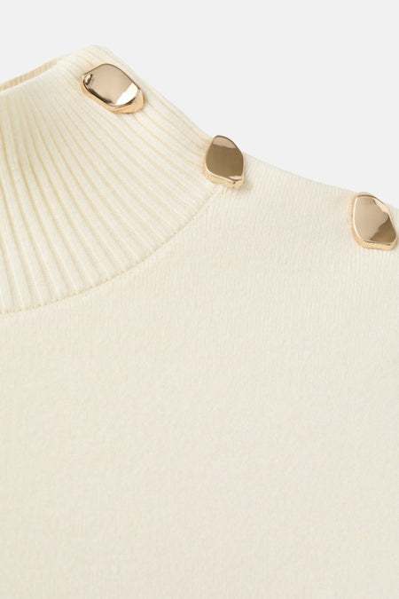 Ivoorwit gebreide trui met gouden knopen op de schouder.