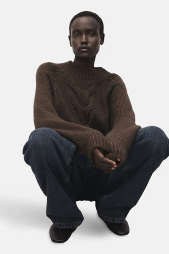 Pull marron avec col rond de MANGO, à motif côtelé sur l'avant, associé à des jeans foncés et des chaussures noires.