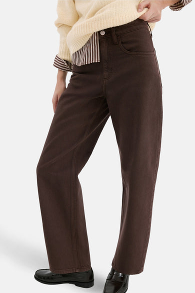 Jean bleu de MANGO, décontracté et avec des poches, associé à une chemise crème et à des chaussures noires.