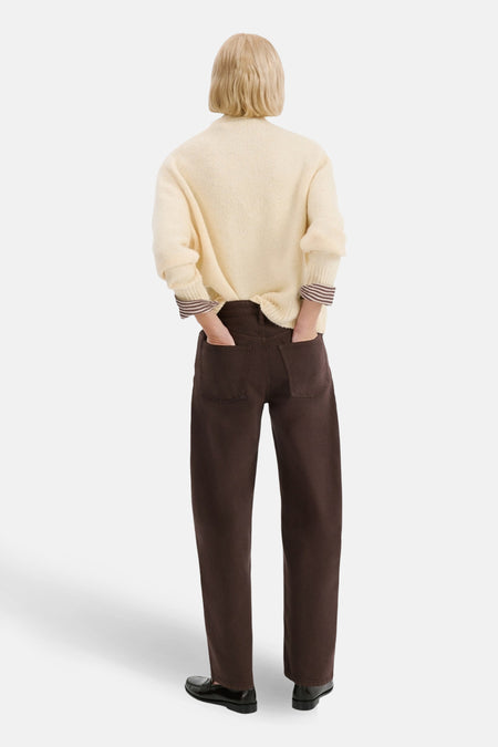 Bruine gekleurde jeans van MANGO, losvallend en met zakken, gecombineerd met een crèmekleurige trui en zwarte schoenen.
