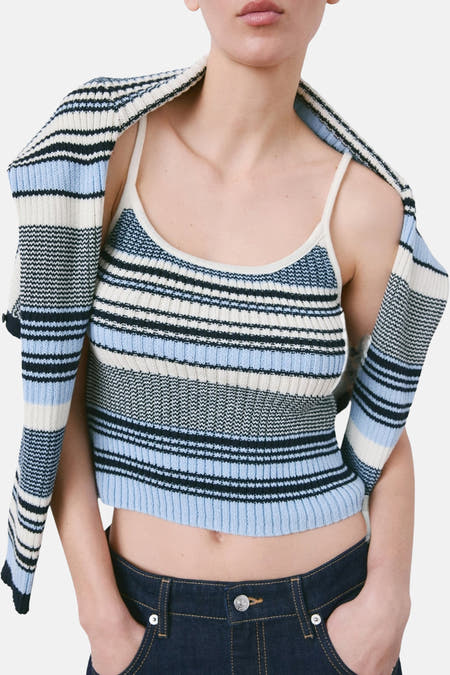 Multikleurige top met spaghettibandjes van MANGO, gestreept patroon met blauwe en witte tinten, gedragen met donkere jeans.
