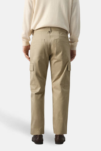 Beige broek van MANGO, gezien van achteren, met steekzakken en bruine schoenen.

