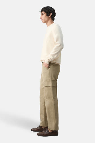 Pantalon beige de MANGO, avec poche cargo, combiné avec un pull crème et des chaussures marron, en vue de côté.
