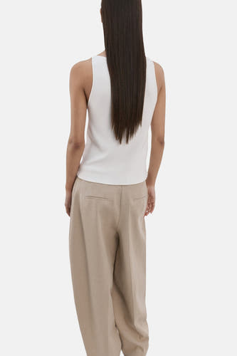 Ecru top zonder mouwen van MANGO, met een strak silhouet en lange bruine haren op de rug.
